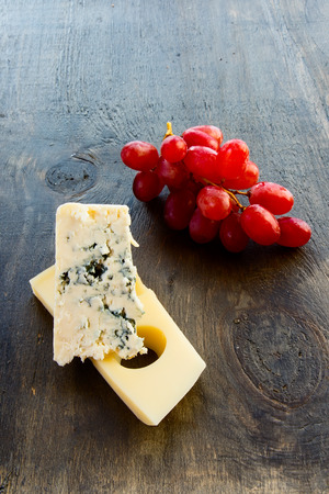 Cheese and grapes over rustic wooden surface. Selective focusの写真素材
