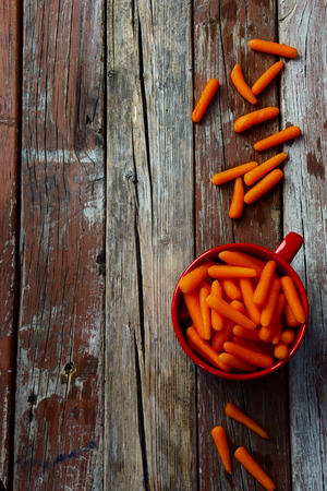 Top view of Baby cut carrots on rustic wooden background.の写真素材