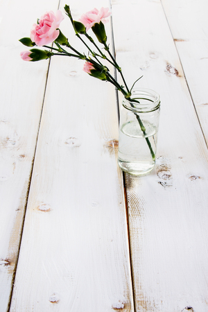 Pinkl flowers in a vase on white wooden texture.の写真素材
