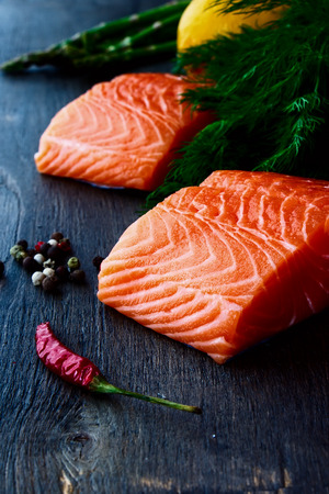 Portion of salmon fillet with aromatic herbs and spices over dark wooden textureの写真素材