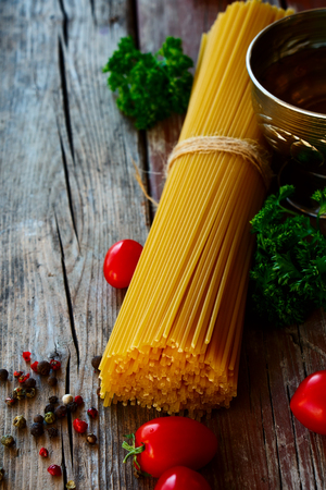 Spaghetti and tomatoes with herbs over rustic and vintage wooden background. Selective focus.の写真素材