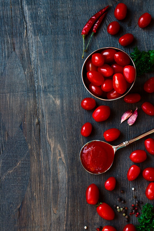 Top view of tomato sauce, tomatoes and spices on wood background with copyspace.の写真素材