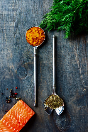 Top view of salmon fillet with aromatic herbs and spices over dark wooden textureの写真素材