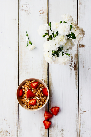 Bowl with cereals and fresh berries for healthy breakfast on white wooden table. Top view.の写真素材