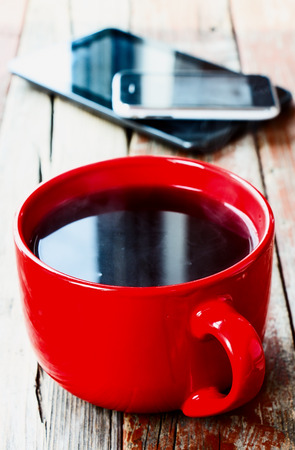 Cup of coffee and digital tablet on old wooden desk. Simple workspace or coffee break in morning selective focusの写真素材