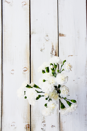 Beautiful flowers in a vase on white wooden texture. Top view.の写真素材