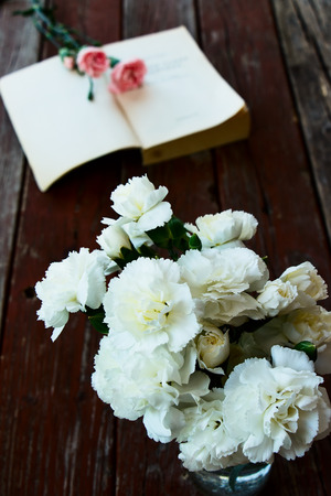 Bouquet white flowers and book on wooden background. Selective focus.の写真素材