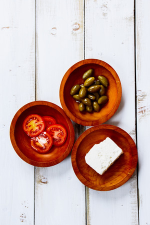 Ingredients for salad with feta, tomatoes and olives on white wooden background. Vegetarian food, health or cooking concept. Top view.の写真素材