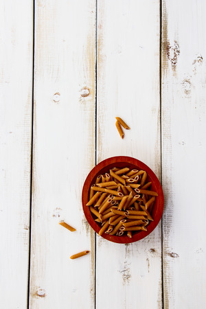 Whole wheat pasta on white wooden background. Top view.の写真素材