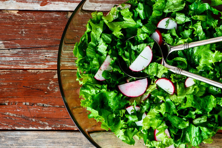 Closeup of salad with lettuce and radishes on rustic wooden texture. Top view.の写真素材