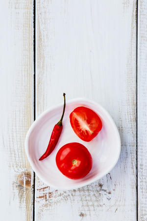 Fresh tomatoes and chili pepper ketchup ingredients on white wooden texture. Top view.の写真素材