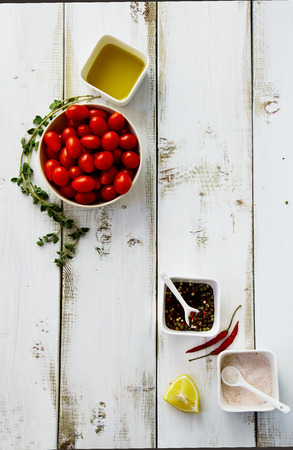 Food background with tomatoes, herbs, spices, olive oil, pink salt and lemons on white wooden board. Top view.の写真素材