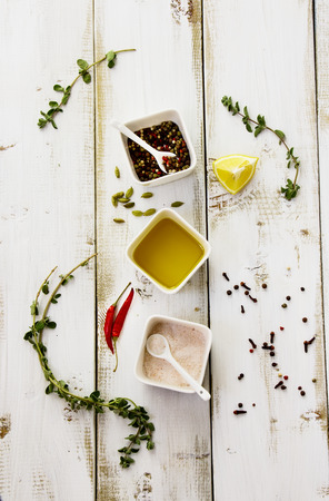 Herbs, spices, olive oil, pink salt and lemons on white wooden board. Top view.の写真素材