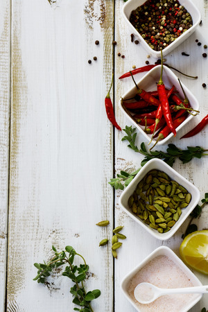 Colorful spices and herbs over white wooden backgroundの写真素材