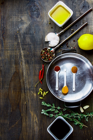 Food background with herbs, spices, olive oil, pink salt and lemon on dark wooden board. Top viewの写真素材