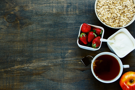 Healthy Breakfast. Oats, berries and tea over dark old wood. Health and diet concept. Top view.の写真素材
