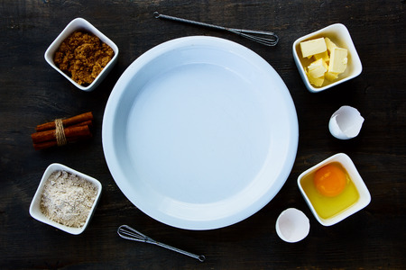 Baking ingredients raw eggs, sugar, butter and flour over dark wood board. Top view. Food background.の写真素材