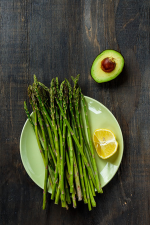 Asparagus and avocado on dark wooden background. Vegetarian food, health or cooking concept. Top view.の写真素材