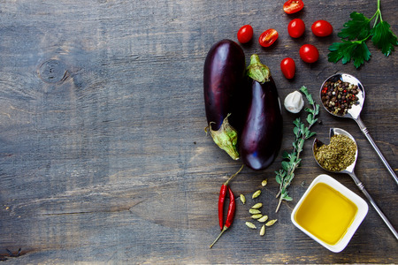 Fresh eggplants with aromatic herbs, spices and vegetables on a Wooden Background. Vegetarian food, health or cooking concept.の写真素材