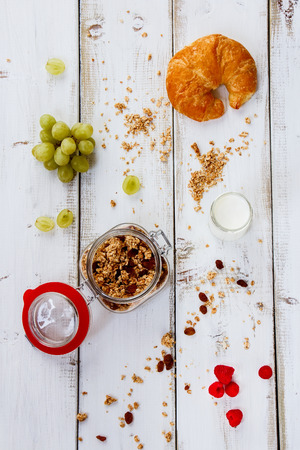 Healthy breakfast. Granola, muesli, yogurt, grape, fresh berries and croissant on white wooden background. Health and diet concept. Top view.の写真素材