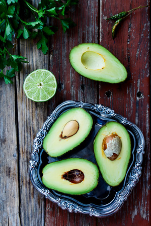 Halved avocados on vintage wooden background - healthy food, diet or cooking concept. Top view.の写真素材