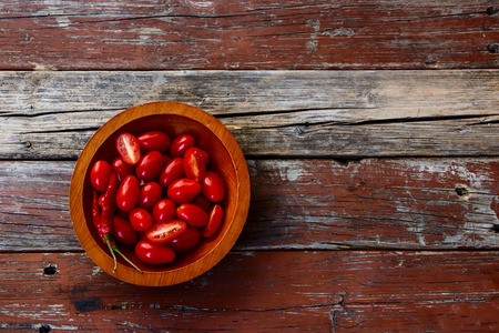 Top view of fresh red delicious tomatoes in wooden plate on rustic wooden background with place for text.の写真素材