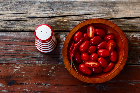 Fresh delicious tomatoes in wooden plate on rustic wooden background. Top view.の写真素材