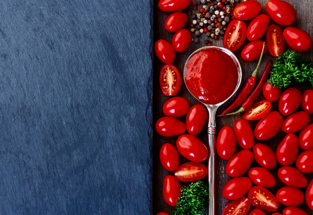 Food background with tomato sauce, tomatoes and spices. Slate and wood background with copyspace. Top view.の写真素材