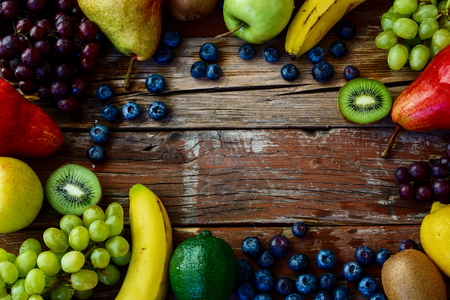 Different fresh fruits on rustic wooden board. Healthy eating background. Top view.の写真素材