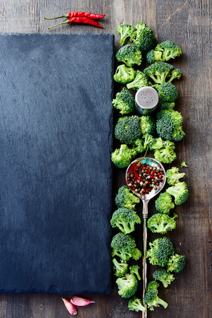 Food background with fresh green broccoli and spices. Slate and wood background with copyspace. Top view.の写真素材