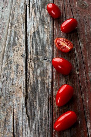 Red fresh tomatoes over rustic wooden texture with copy spaceの写真素材