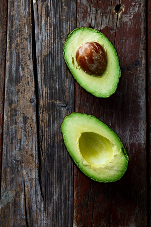 Halved avocados on rustic wooden background. Top view.の写真素材