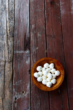 Mozzarella cheese in wood bowl on rustic wooden background, top viewの写真素材