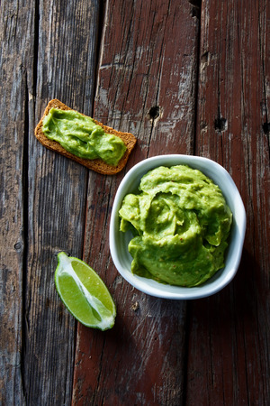 Freshly Homemade Guacamole with bread toast on rustic wooden background.Top view.の写真素材