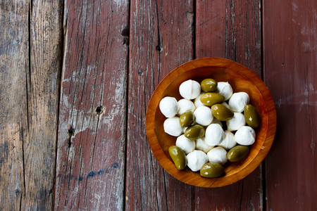 Mozzarella cheese and green olives in wood bowl on rustic wooden background, top viewの写真素材