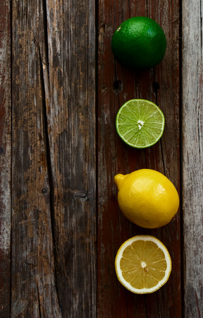 freshly cut half and whole lemons and limes on rustic wooden texture. Top view.の写真素材