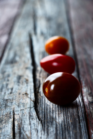 Mix of three tomatoes on rustic wooden surface. Selective focusの写真素材