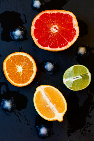 Set of sliced citrus fruits lemon, lime, orange, grapefruit and ice over metal texture. Top viewの写真素材