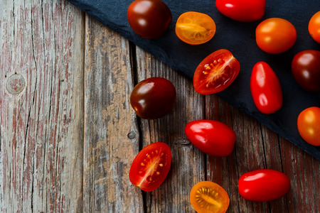 Mix of tomatoes over rustic wooden texture with copy space. Top view.の写真素材