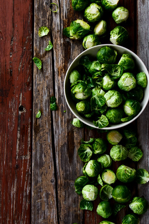 Top view of organic brussel sprouts in a white bowl on rustic wooden table.の写真素材