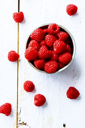 Top view of organic raspberry in bowl on white wooden board.の写真素材