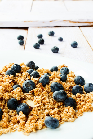 Healthy multi-grain granola with fresh blueberries on white wooden background. Selective focus.の写真素材