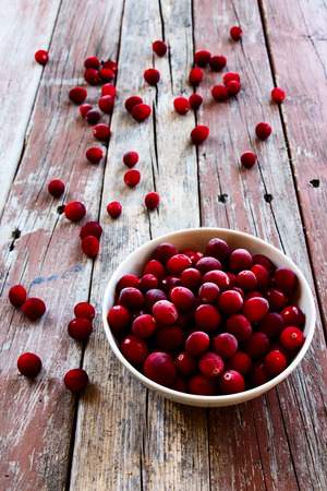 Cranberries in ceramic bowl on rustic wooden background. Selective focusの写真素材