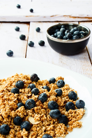 Delicious multi-grain granola with fresh blueberries on white wooden background. Selective focus.の写真素材