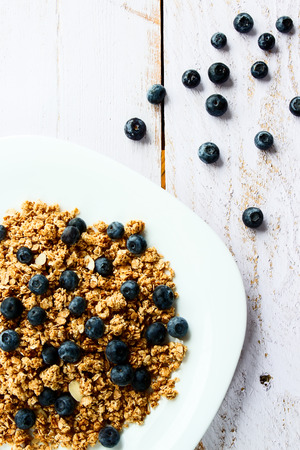 Delicious and healthy multi-grain granola with fresh blueberries on white wooden background. Top view.の写真素材