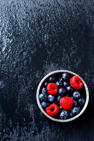 Mix of ripe berries in bowl on dark grey background. Top view.の写真素材