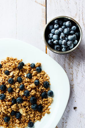 Top view of healthy multi-grain granola with fresh blueberries on white wooden background.の写真素材