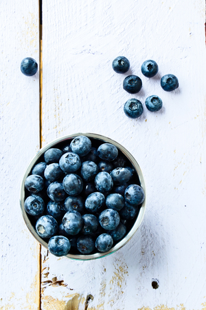 Bowl of fresh blueberries on white wooden background. Top view.の写真素材