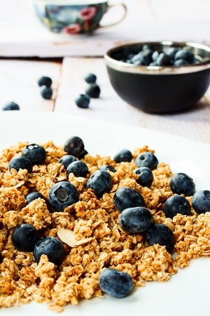 Multi-grain granola with fresh blueberries for breakfast on white wooden background. Selective focus.の写真素材