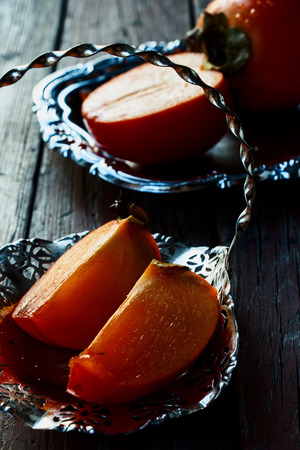 Organic slice persimmon on rustic wooden background. Selective focus.の写真素材